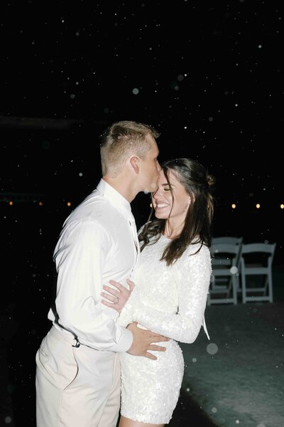 Bride and groom kissing at their Colorado wedding reception outside in the snow, on flash