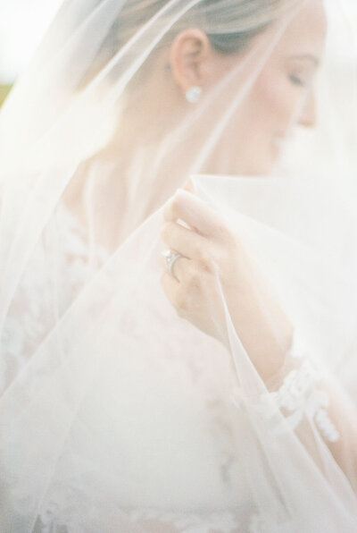 Bride under white veil smiles softly