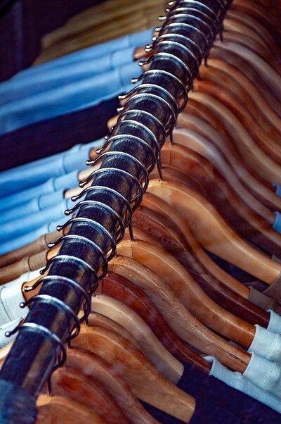A close-up over the top of many clothes hangars hanging on a black pole.
