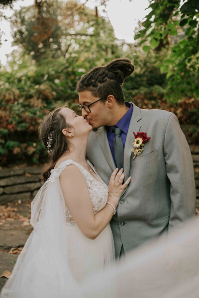Married couple kiss with veil in the forground.