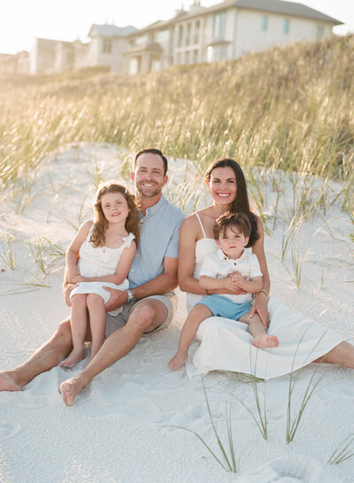 family of four sitting at the edge of the dunes at Grayton Beach