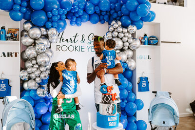 woman smiling and holding baby with balloons in background