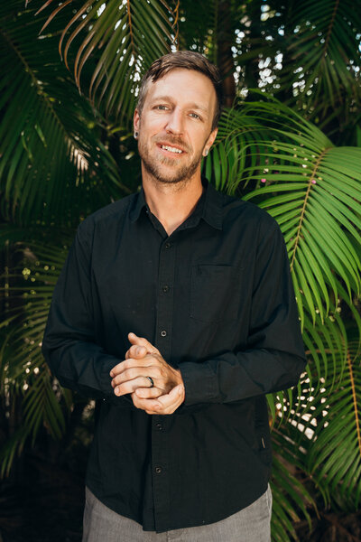 Drone Wedding Photographer, Chris Wolfe, standing in black shirt before sunset beach wedding