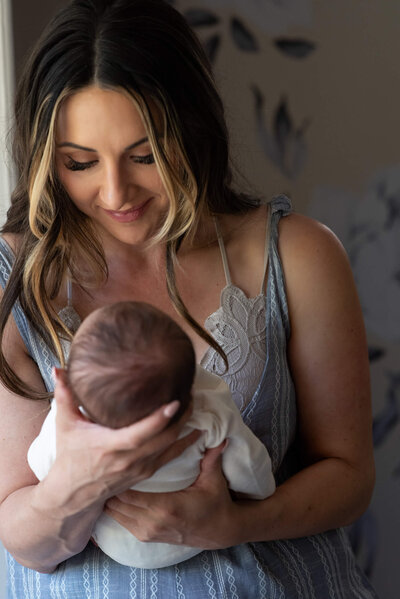 New mom holding and admiring her newborn baby girl in her home in Colorado Springs