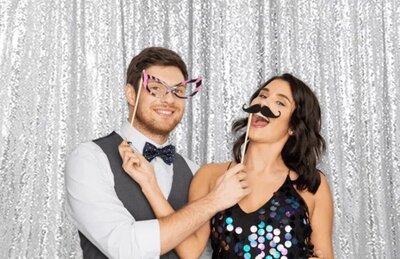 Couple being silly in front of silver sequin backdrop