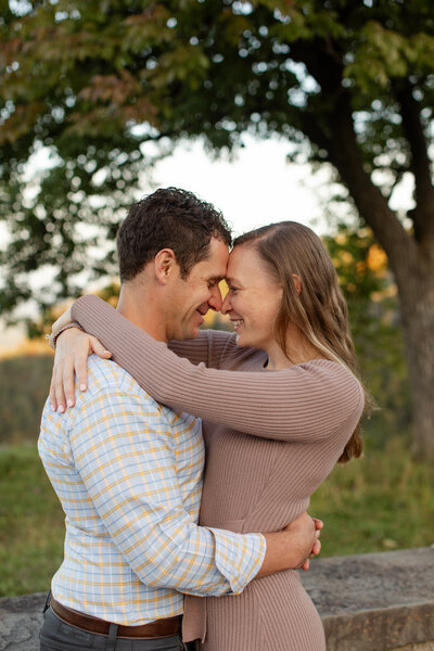 Engaged couple smile at each other while their foreheads touch