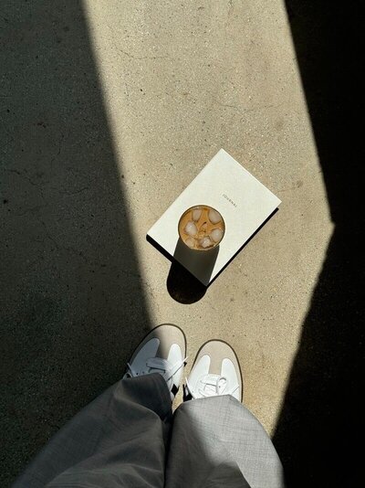 An employee's feet next to a cup of coffee and a book, symbolizing a break from Showit website design services.

