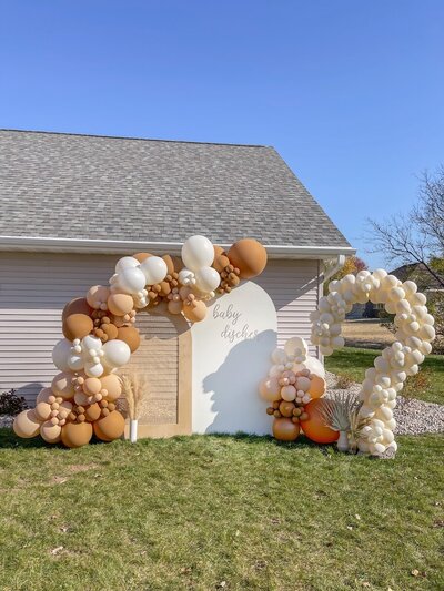 Boho gender reveal party decorations with neutral balloons and wooden backdrops