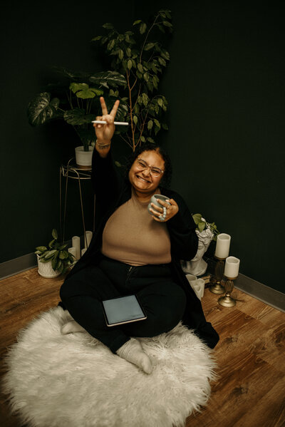 Ashley holding out a peace sign with her coffee and iPad scheduler.