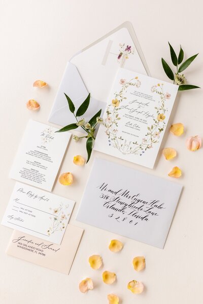 Wedding invitation suite with yellow wildflowers, peach accents, and botanical liner