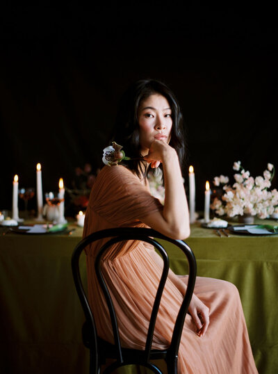 Woman pensively sitting with flower in front of styled table in Los Angeles