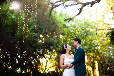 Bride and groom laughing and holding hands amid the nature at Green Gables Wedding Estate wedding venue in San Marcos.