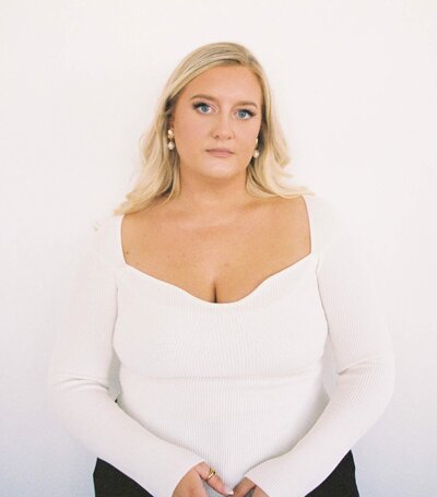 Wedding Photographer Leslie DeAnn stands in a studio in a white top