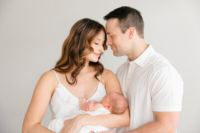 father looks lovingly at his wife as she looks down at their newborn baby during a newborn portrait session with Indianapolis photographer Brittney Lear