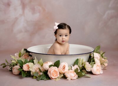 Baby girl in a tub with pink flowers around the basin. Photo taken at the Woodstock Portrait studio in Georgia