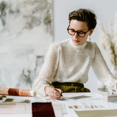 Elegant woman reviewing swatches and sketches at a design table, symbolizing creative learning and strategic brand development