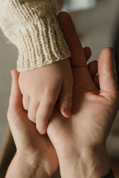 Image of two adult hands holding a small child's hand