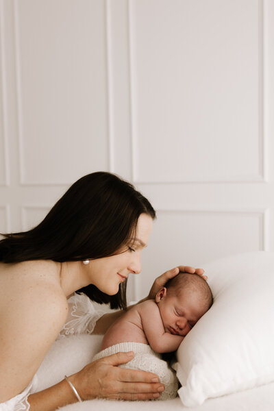 Mum gently cradling and resting forehead to newborn’s head during soft and natural newborn photoshoot in Southwest Sydney studio