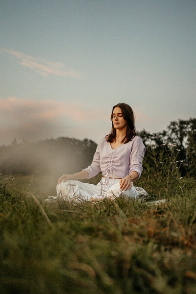 Tessa Adrian in einer meditativen Yoga-Haltung im Grünen, voller Achtsamkeit.