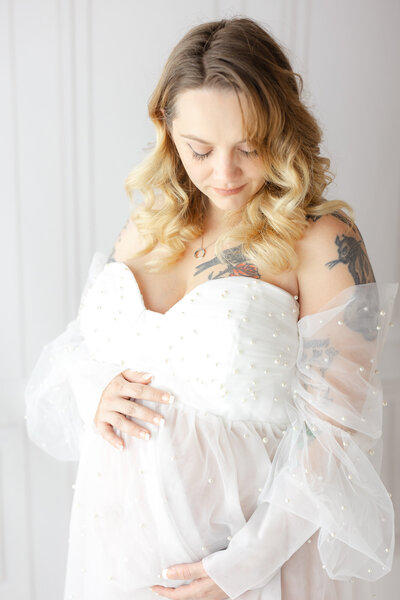 Mom looking and holding her baby bump at a studio maternity session in Savannah, Ga
