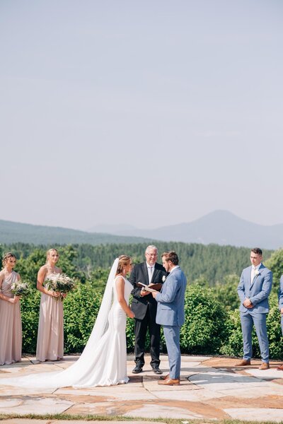 Bride and groom during their wedding ceremony with the blue ridge mountains in the backdrop.