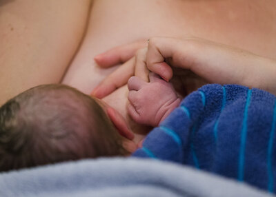 A new baby holds her mothers hand.