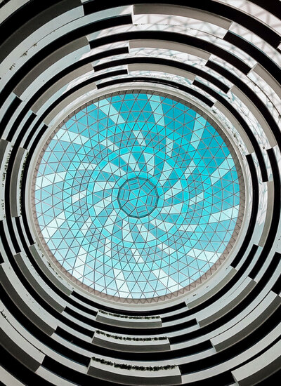 A blue spiral of stained glass on the ceiling of a tall building