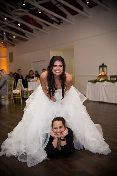photographer laying under bride's dress while they both smile