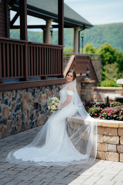 bride sitting on a rock wall bolding her bridal bouquet