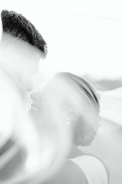 Bride smiles at groom as veil sways in the wind in Cape Cod