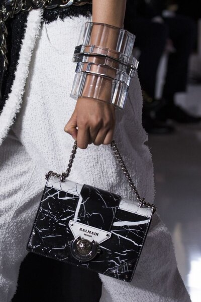 A person carrying a black and white luxury handbag