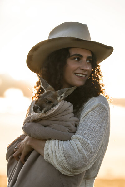 woman wearing a cowboy hat in a camera harness walking in a field
