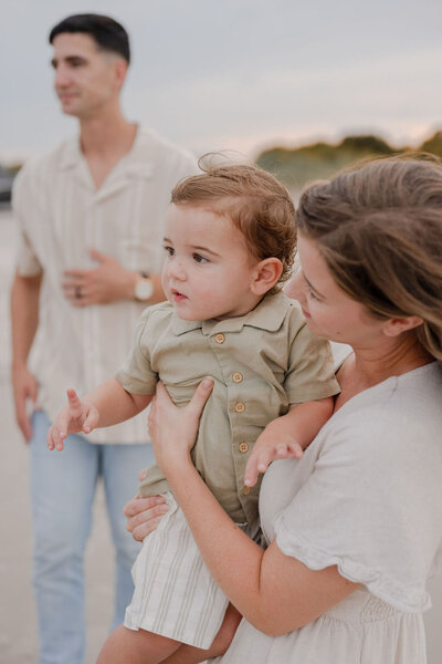 a family of three gazing into the distance on the beach
