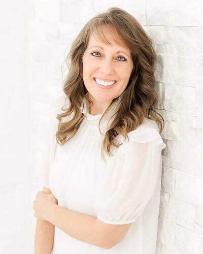 North East, PA, family photographer near Erie, PA, Jennifer Hall, by a white wall.