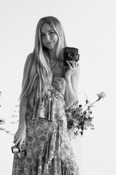 sunnie heers, photographer, posing with her camera and wildflowers