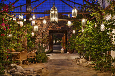 An outdoor wedding ceremony setup featuring wooden chairs and a floral arch on a green lawn.