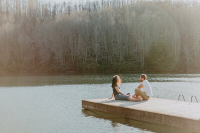 photo of adventurous couple sitting on a pier by a lake outside of Asheville