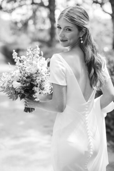 Bride looks over her shoulder while carrying bouquet