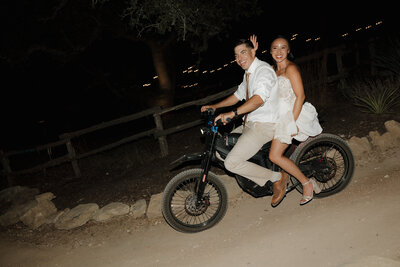 Bride and groom leave their reception on a motorcycle. 