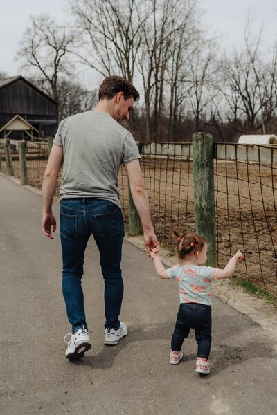 father walking with toddler daughter at zoo