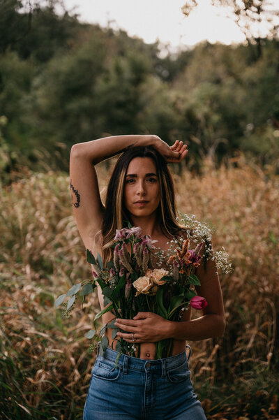 Woman in a field holds flowers