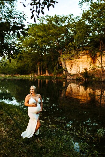 pregnant woman in a white dress next to a river