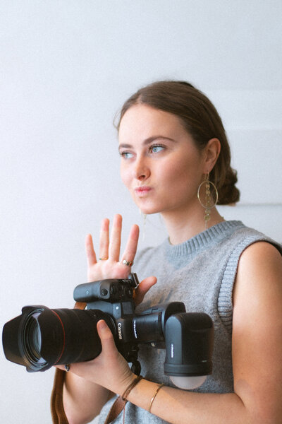 Bo Eppink, a professional photographer, playfully poses with her digital camera, demonstrating camera settings during a fun photography shoot with Eloise van Oranje.
