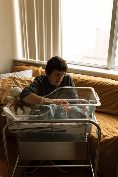dad holding newborn baby's hand in hospital