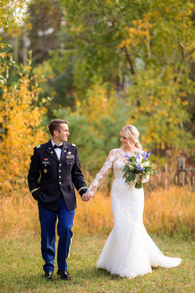 wedding couple walk hand in hand through CO meadow