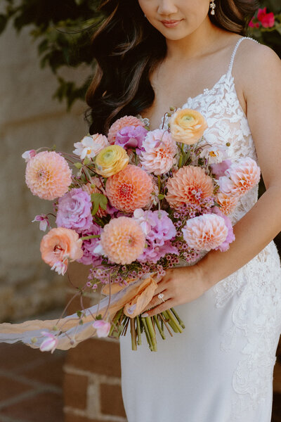 Black bride with long braids holding a colorful bouquet