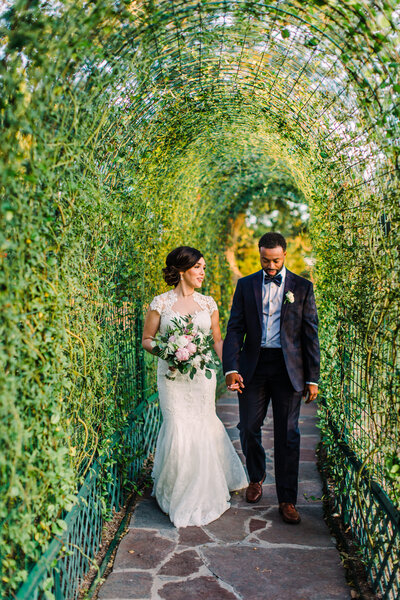 couple walking through tunnel of greenery on their wedding day at Ma Maison wedding venue