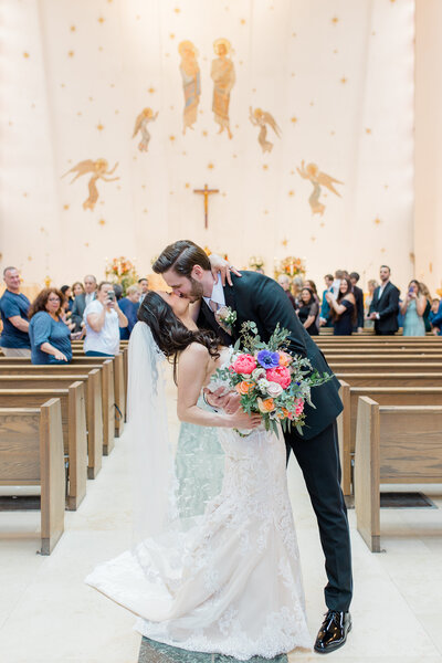 Couple kissing down the aisle of Catholic Church wedding