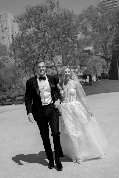 A candid photo of a bride and groom holding hands and smiling.