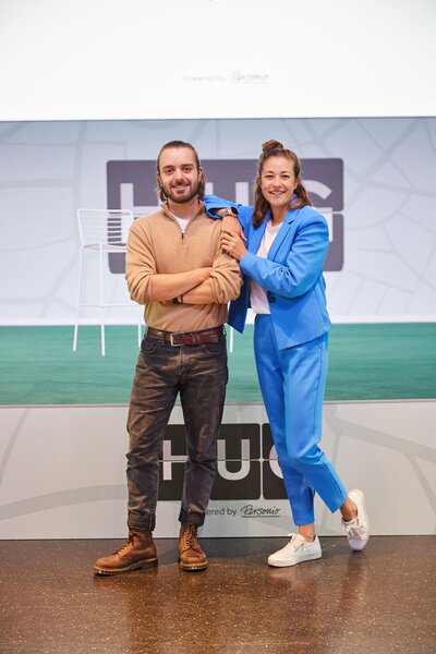 Moderatorin Hanna Zöller im blauen Anzug beim HUG Festival, gemeinsam mit Co-Moderator auf der Bühne